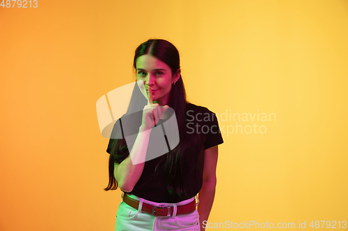 Image of Caucasian young woman\'s portrait on yellow background in neon light