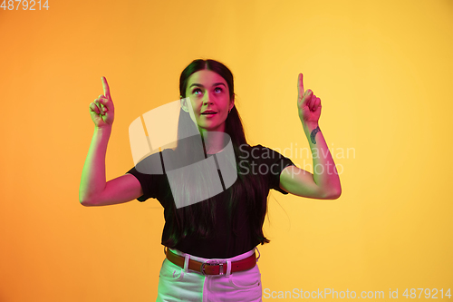 Image of Caucasian young woman\'s portrait on yellow background in neon light