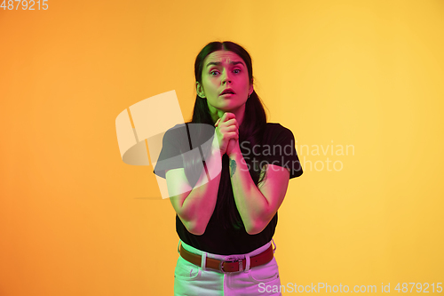 Image of Caucasian young woman\'s portrait on yellow background in neon light