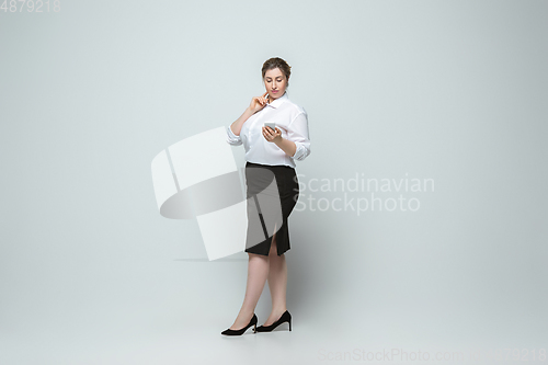 Image of Young caucasian woman in office attire on gray background. Bodypositive female character. plus size businesswoman