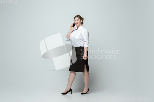 Image of Young caucasian woman in office attire on gray background. Bodypositive female character. plus size businesswoman