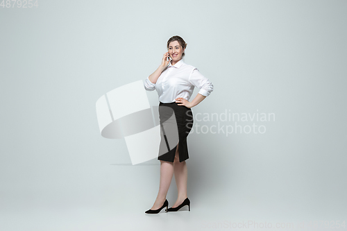 Image of Young caucasian woman in office attire on gray background. Bodypositive female character. plus size businesswoman