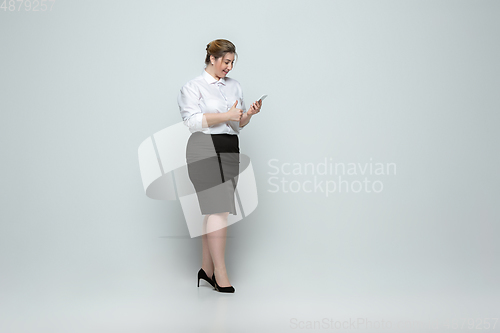 Image of Young caucasian woman in office attire on gray background. Bodypositive female character. plus size businesswoman
