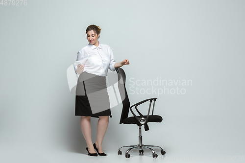 Image of Young caucasian woman in office attire on gray background. Bodypositive female character. plus size businesswoman