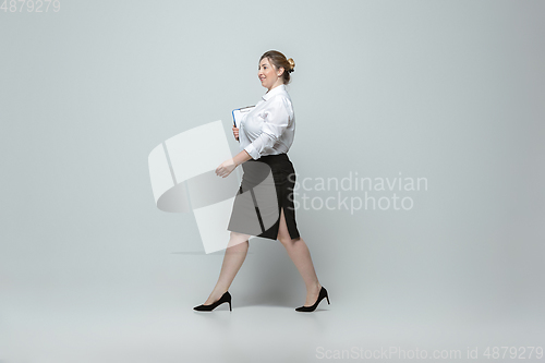 Image of Young caucasian woman in office attire on gray background. Bodypositive female character. plus size businesswoman