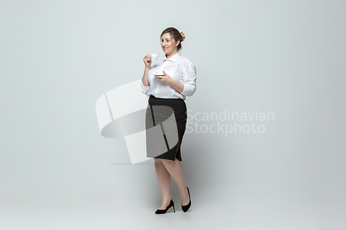 Image of Young caucasian woman in office attire on gray background. Bodypositive female character. plus size businesswoman