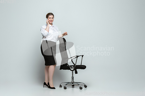 Image of Young caucasian woman in office attire on gray background. Bodypositive female character. plus size businesswoman