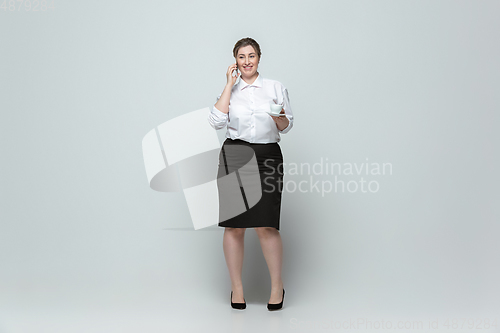 Image of Young caucasian woman in office attire on gray background. Bodypositive female character. plus size businesswoman