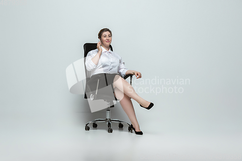 Image of Young caucasian woman in office attire on gray background. Bodypositive female character. plus size businesswoman
