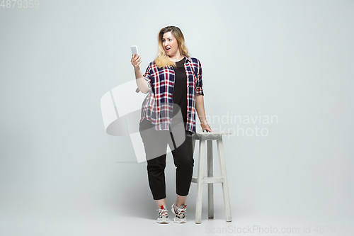 Image of Young caucasian woman in casual wear on gray background. Bodypositive female character, plus size businesswoman