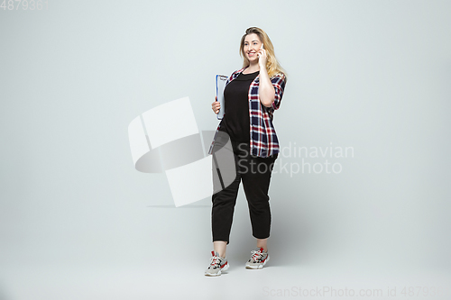 Image of Young caucasian woman in casual wear on gray background. Bodypositive female character, plus size businesswoman