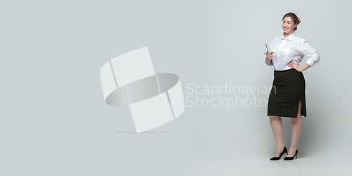 Image of Young caucasian woman in office attire on gray background. Bodypositive female character. plus size businesswoman