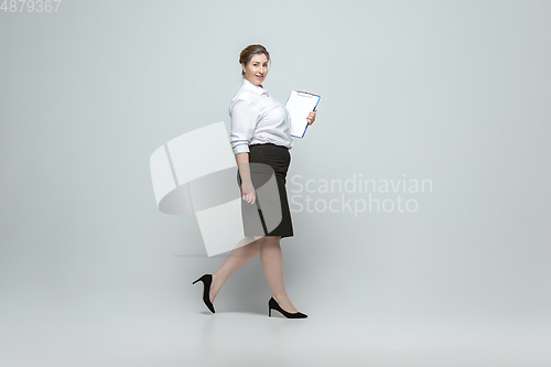 Image of Young caucasian woman in office attire on gray background. Bodypositive female character. plus size businesswoman