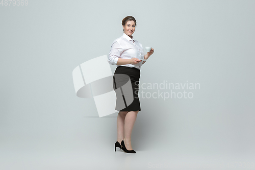 Image of Young caucasian woman in office attire on gray background. Bodypositive female character. plus size businesswoman