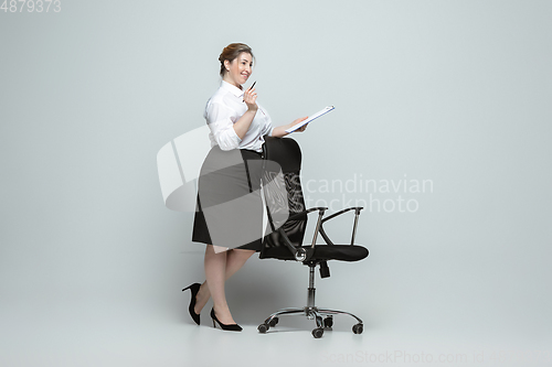 Image of Young caucasian woman in office attire on gray background. Bodypositive female character. plus size businesswoman