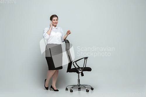 Image of Young caucasian woman in office attire on gray background. Bodypositive female character. plus size businesswoman