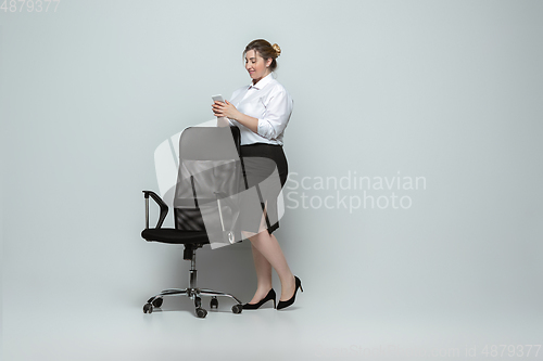 Image of Young caucasian woman in office attire on gray background. Bodypositive female character. plus size businesswoman