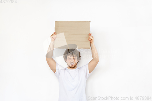 Image of Young man protesting with blank board, sign isolated on white studio background