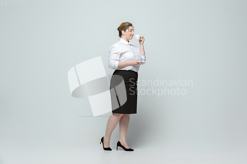 Image of Young caucasian woman in office attire on gray background. Bodypositive female character. plus size businesswoman
