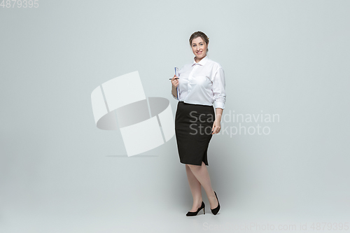 Image of Young caucasian woman in office attire on gray background. Bodypositive female character. plus size businesswoman