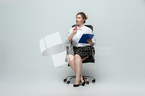 Image of Young caucasian woman in office attire on gray background. Bodypositive female character. plus size businesswoman