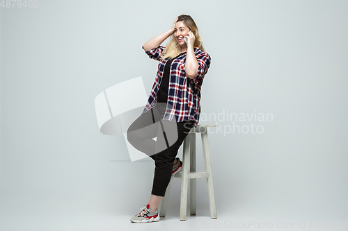 Image of Young caucasian woman in casual wear on gray background. Bodypositive female character, plus size businesswoman