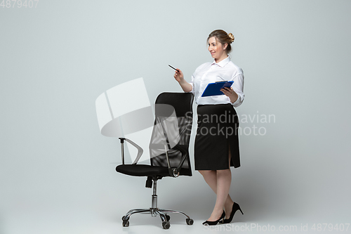 Image of Young caucasian woman in office attire on gray background. Bodypositive female character. plus size businesswoman