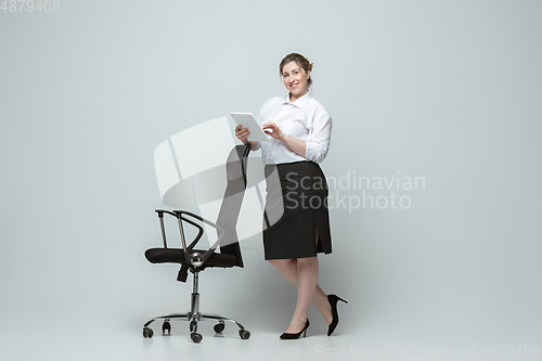 Image of Young caucasian woman in office attire on gray background. Bodypositive female character. plus size businesswoman