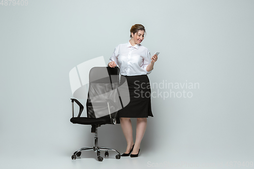 Image of Young caucasian woman in office attire on gray background. Bodypositive female character. plus size businesswoman