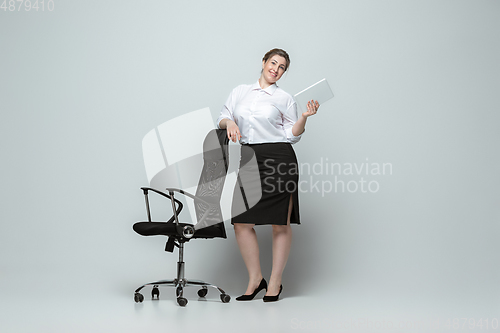 Image of Young caucasian woman in office attire on gray background. Bodypositive female character. plus size businesswoman