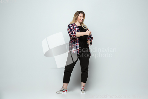 Image of Young caucasian woman in casual wear on gray background. Bodypositive female character, plus size businesswoman