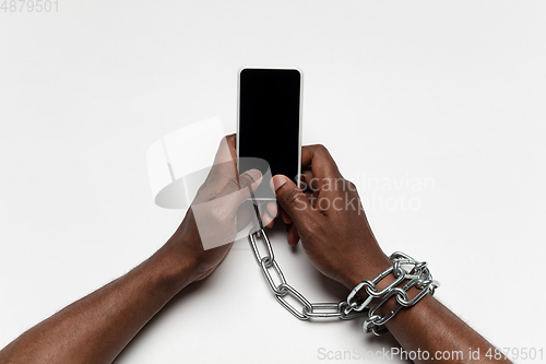 Image of Close up of human hand using smartphone with blank black screen. Tied with chain, addiction