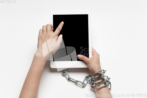 Image of Close up of human hand using tablet with blank black screen. Tied with chain, addiction