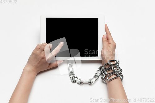 Image of Close up of human hand using tablet with blank black screen. Tied with chain, addiction