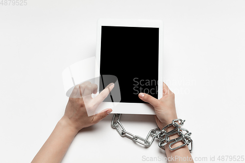 Image of Close up of human hand using tablet with blank black screen. Tied with chain, addiction