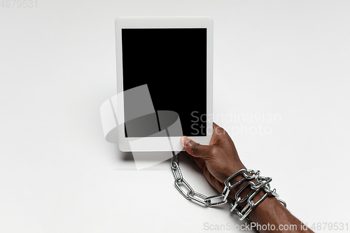 Image of Close up of human hand using tablet with blank black screen. Tied with chain, addiction