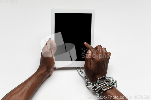 Image of Close up of human hand using tablet with blank black screen. Tied with chain, addiction