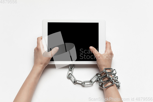 Image of Close up of human hand using tablet with blank black screen. Tied with chain, addiction