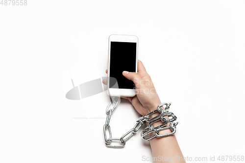 Image of Close up of human hand using smartphone with blank black screen. Tied with chain, addiction