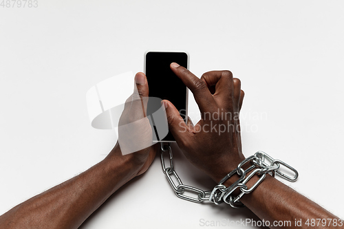 Image of Close up of human hand using smartphone with blank black screen. Tied with chain, addiction