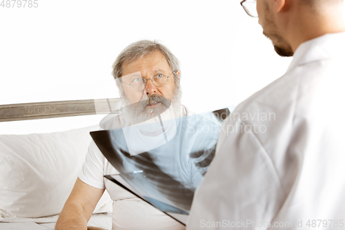 Image of Elderly old man recovering in a hospital bed isolated on white