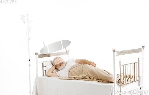 Image of Elderly old man recovering in a hospital bed isolated on white