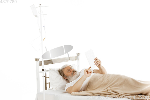 Image of Elderly old man recovering in a hospital bed isolated on white