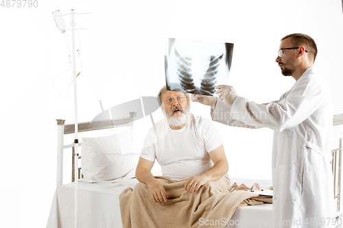 Image of Elderly old man recovering in a hospital bed isolated on white