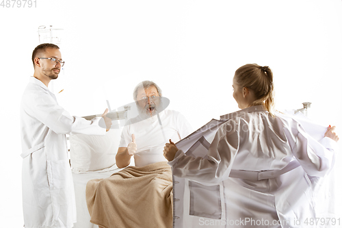 Image of Elderly old man recovering in a hospital bed isolated on white