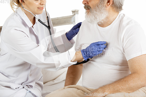 Image of Elderly old man recovering in a hospital bed isolated on white