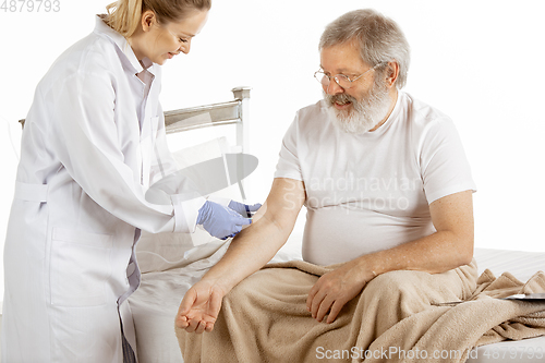 Image of Elderly old man recovering in a hospital bed isolated on white