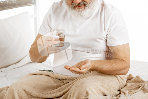 Image of Elderly old man recovering in a hospital bed isolated on white