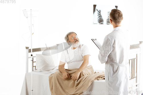 Image of Elderly old man recovering in a hospital bed isolated on white