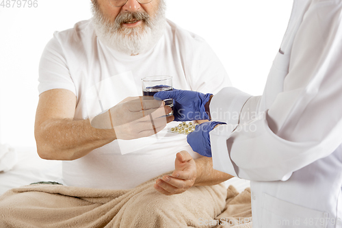 Image of Elderly old man recovering in a hospital bed isolated on white